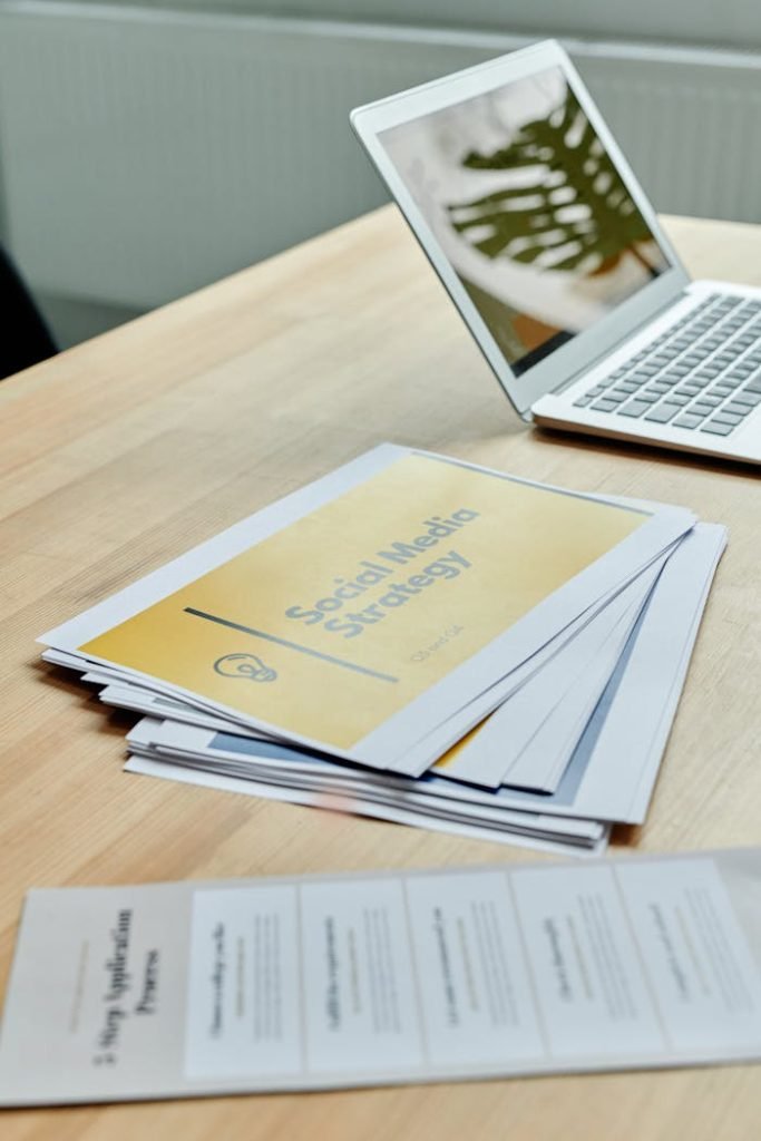 Close-up of social media strategy documents on a desk with a laptop, highlighting office planning.